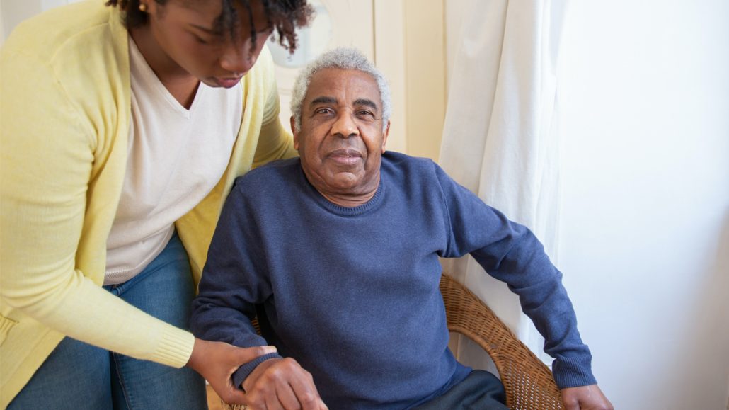 A personal support worker helping a senior stand up
