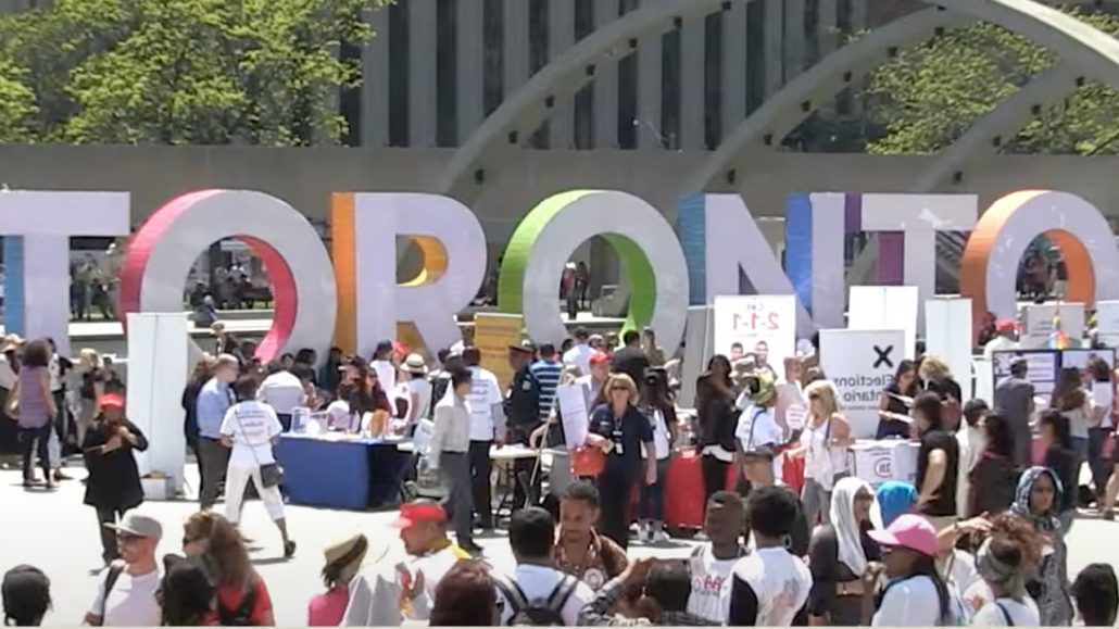 Crowds of people in front of the Toronto sign at Nathan Phillips Square.