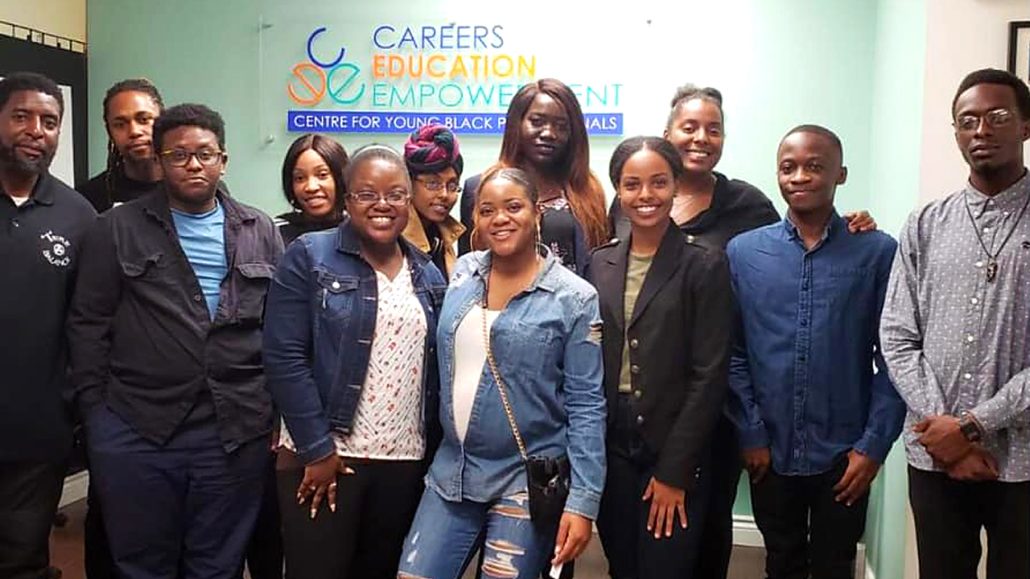 A group of people smiling and standing in front of a sign for CEE Centre For Young Black Professionals.
