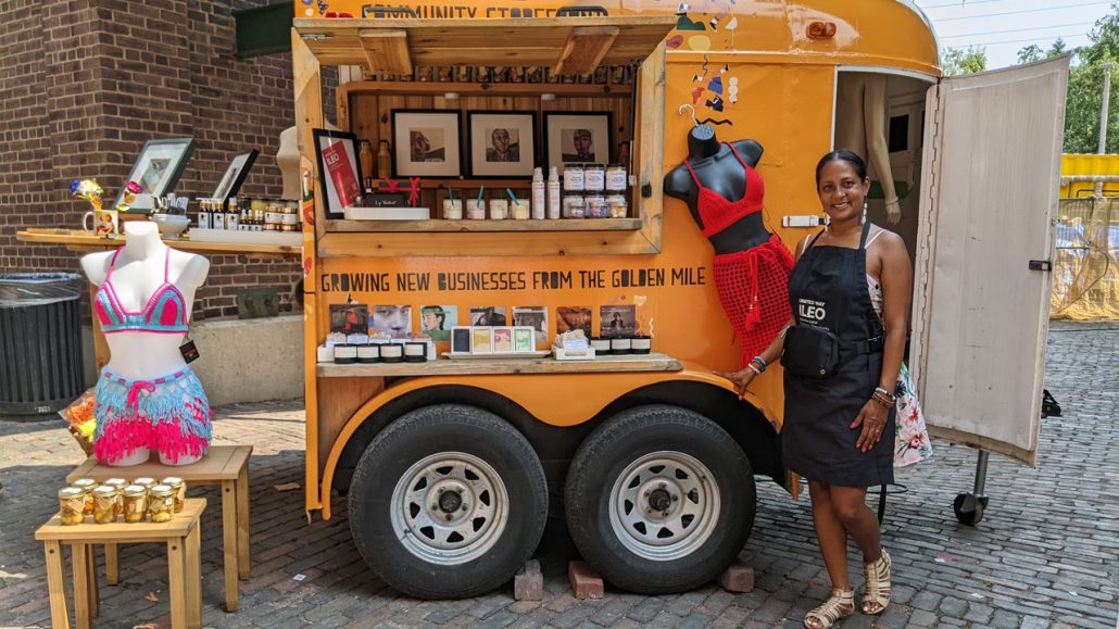 A shop owner at the ILEO Community Storefront in the Distillery District standing in front of a stall.