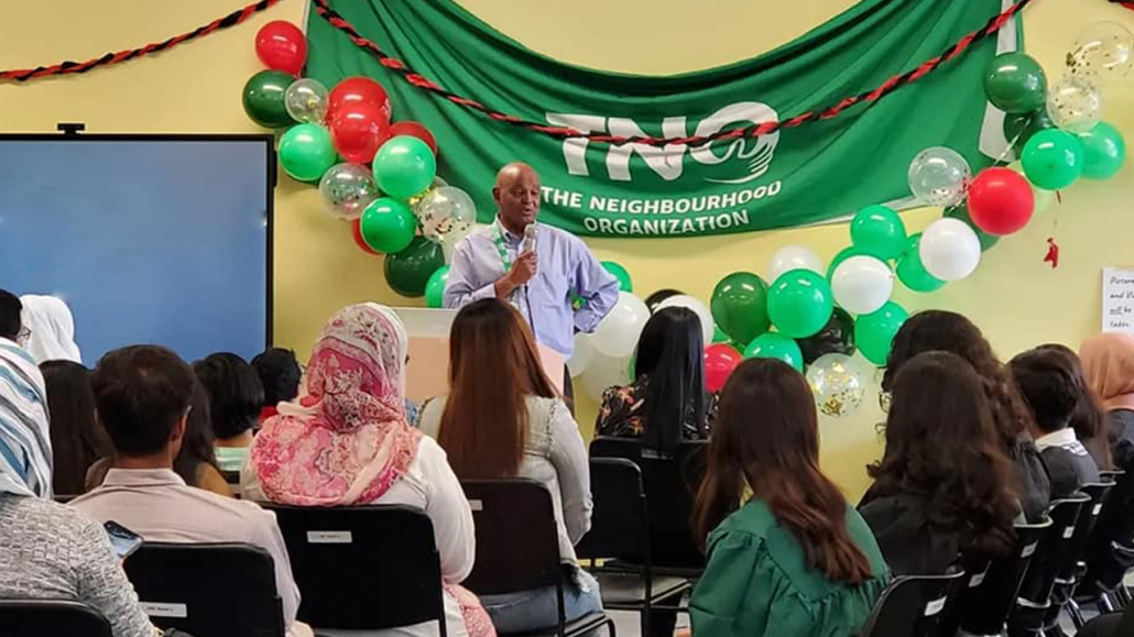 Photo of man presenting at a ceremony at The Neighbourhood Organization