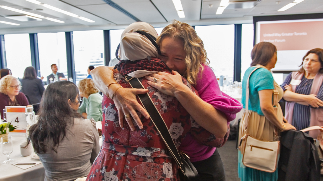 Two women embracing with a hug at a United Way event