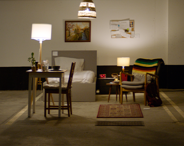 An underground parking space decorated with furniture to look like a one room apartment.