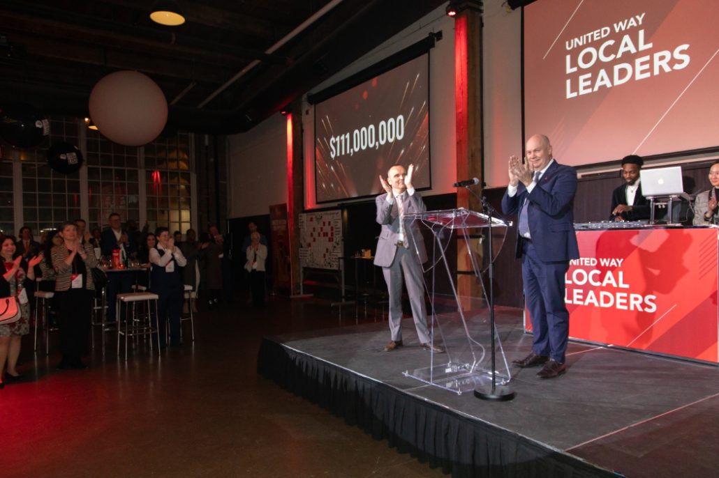 United Way President, Daniele Zanotti and 2023 Campaign Chair, Dave Leonard on stage announcing $111 million goal achievement