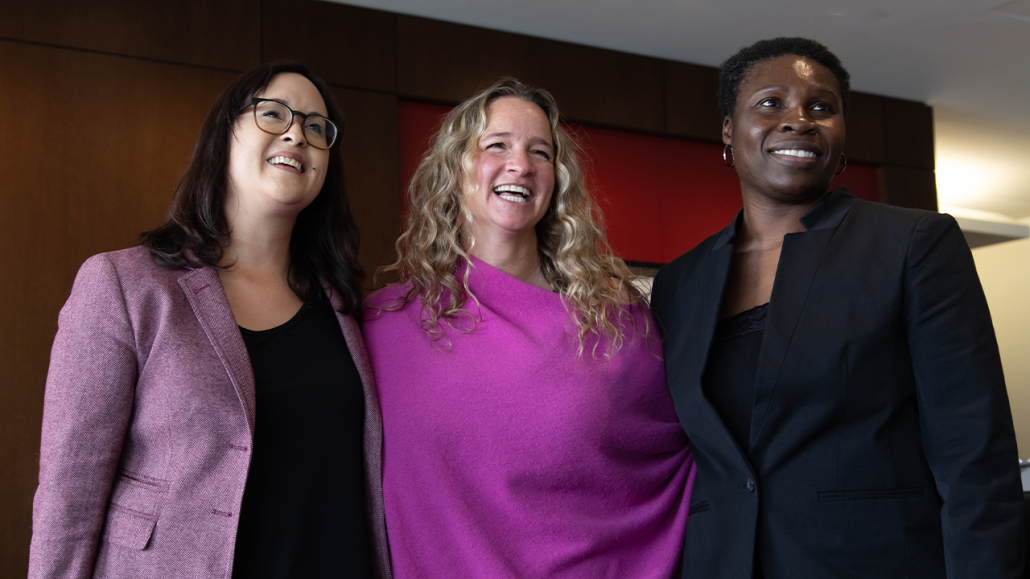 Three agency staff smile at the United Way Greater Toronto Anchor Agency Forum in 2023