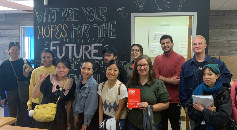 Several students and a teacher standing in front of a chalkboard