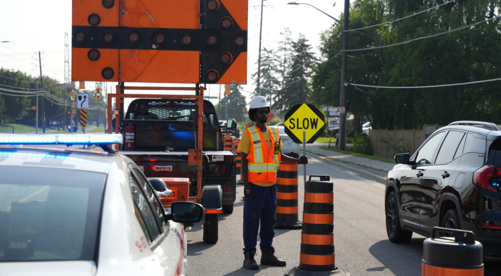 A construction working for the community-based construction company A-GM holds a “slow” sign in front of traffic
