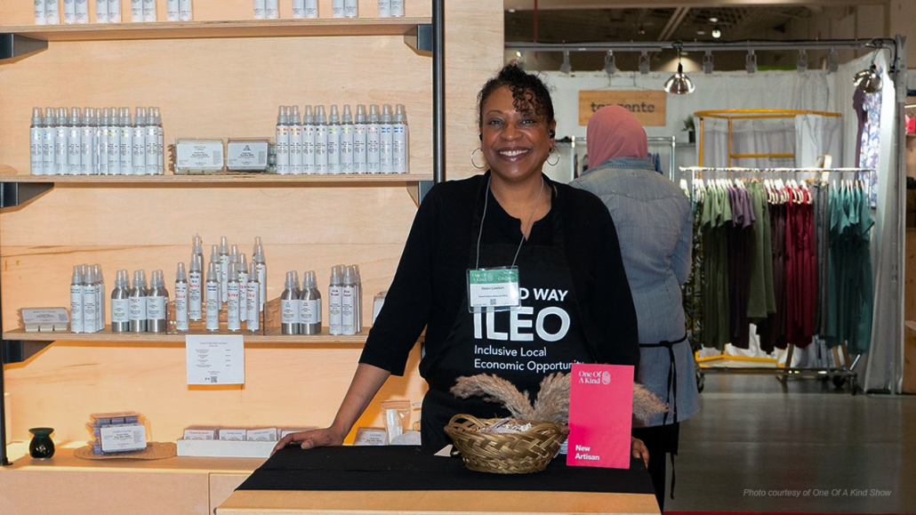 An entrepreneur from United Way's Inclusive Local Economic Opportunity (ILEO) Storefront Starter program standing at a booth featuring their products.