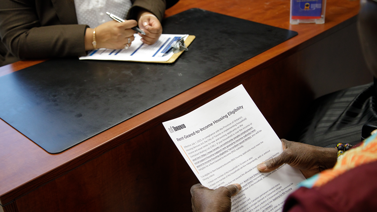 Two people sitting at a desk, filling out a housing application