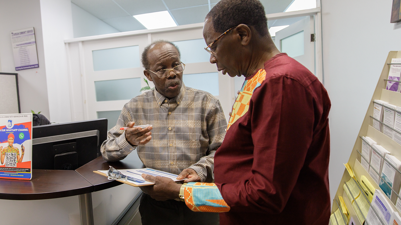 Kwaku, a Program Coordinator at United Way-funded African Community Services of Peel (ACS), helps Boafo fill out some paperwork.