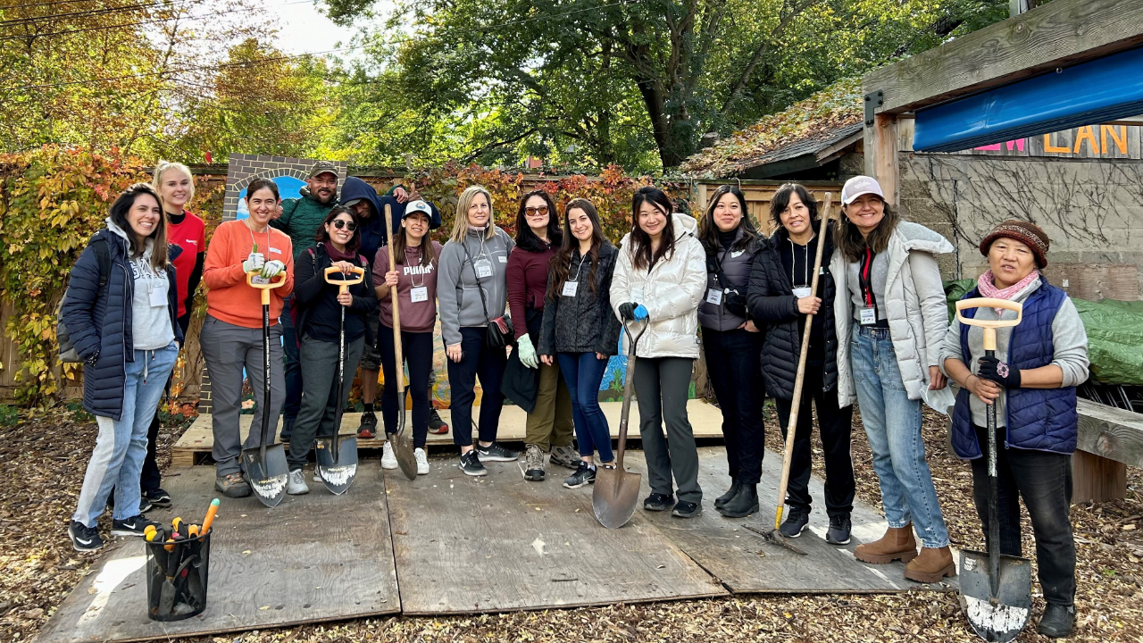 People volunteering in a garden holding rakes and shovels.