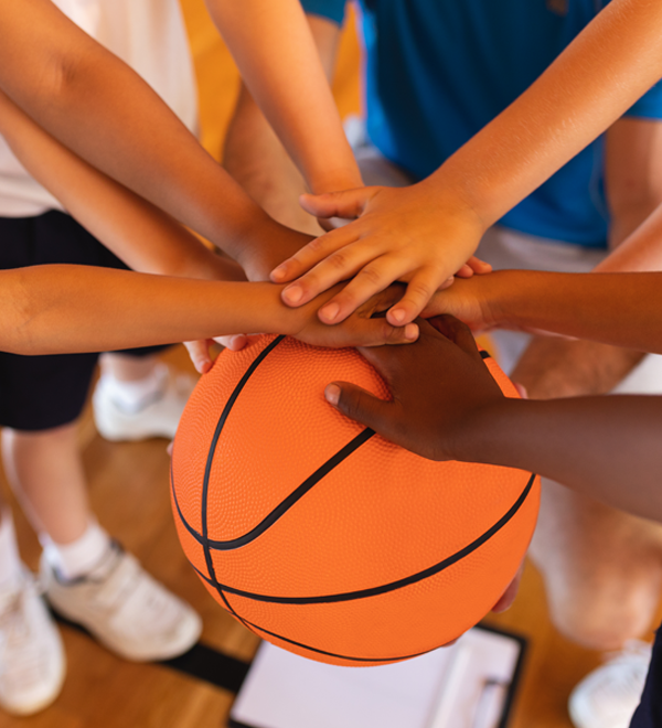 Close-up of hands layered on a basketball.