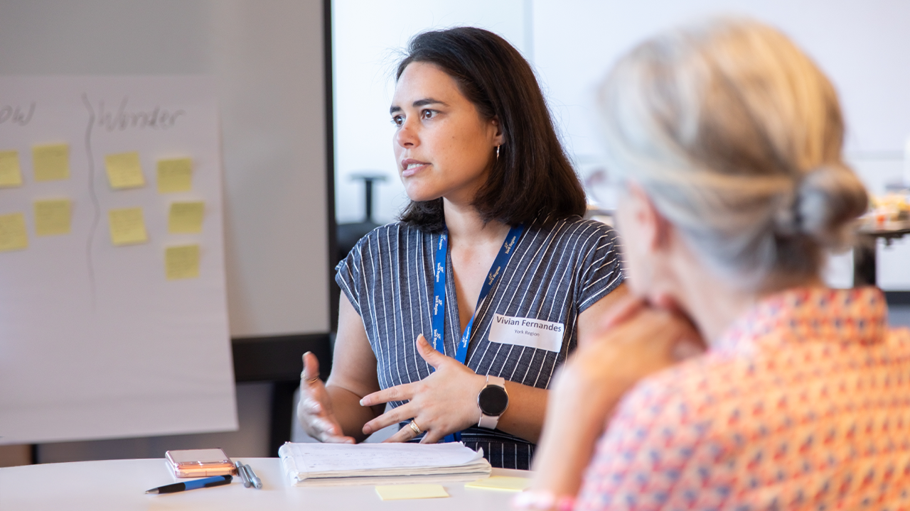 A woman speaking to a group of people at the York Service Partners Table.