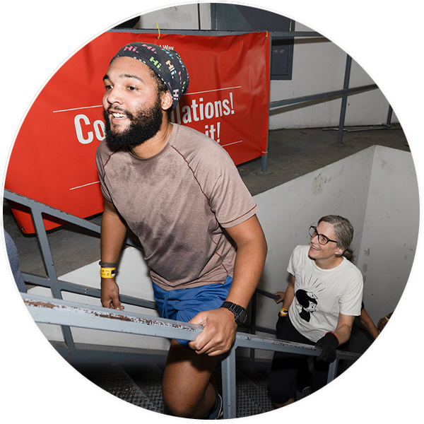 People wearing athletic clothing step up the final stairs at the CN Tower as part of United Way ClimbUP. There is a red ‘Congratulations’ banner in the background.