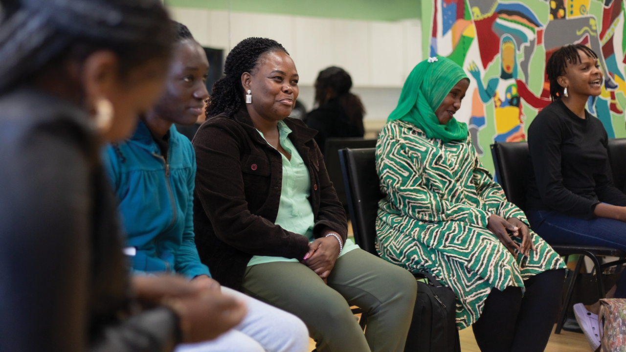 Five Black women sit together smiling.