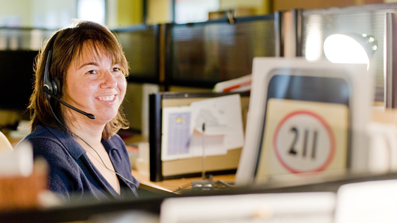 A woman wearing a headset connects callers to community services through 211.
