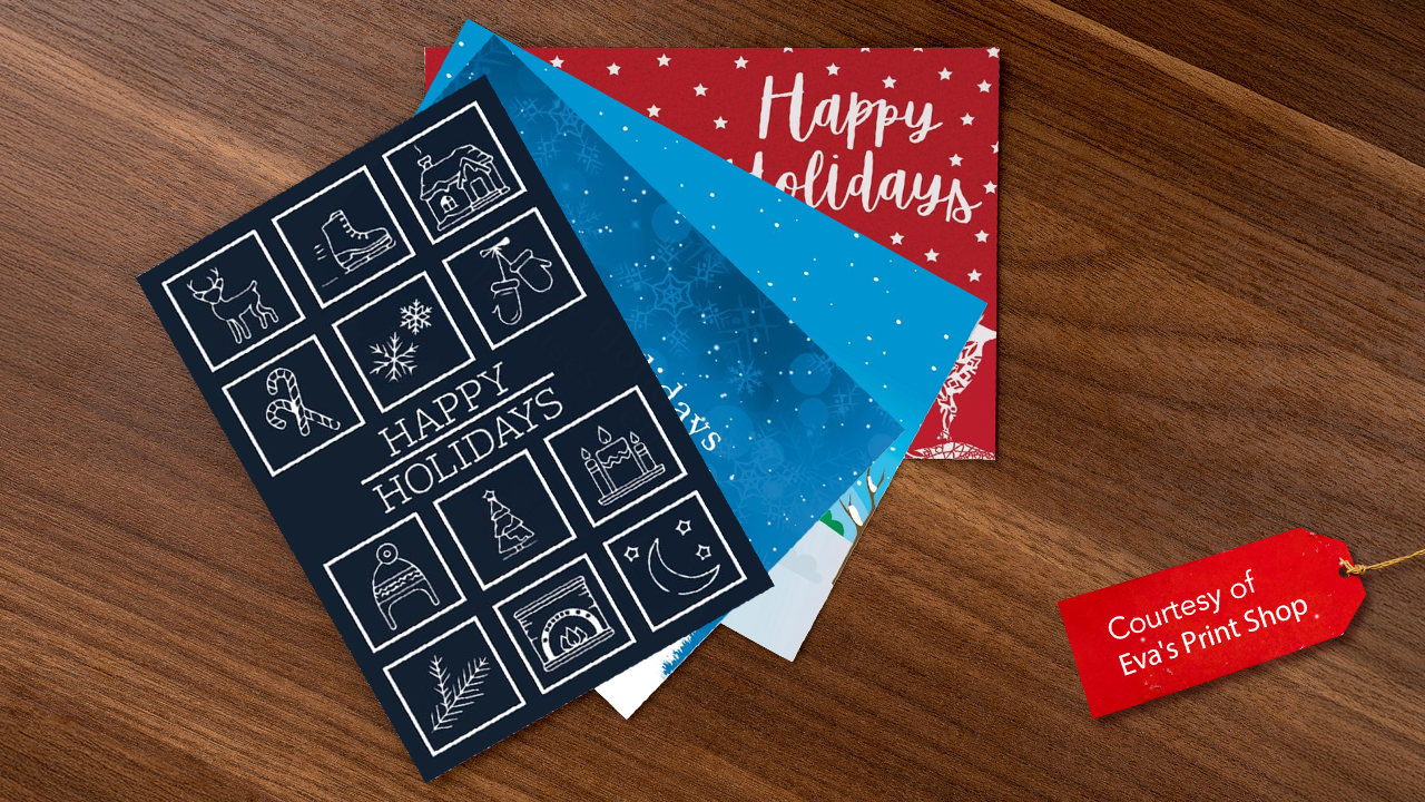 Four holiday greeting cards on a wooden surface with a red gift tag icon with white text that says "Courtesy of Eva's Print Shop"