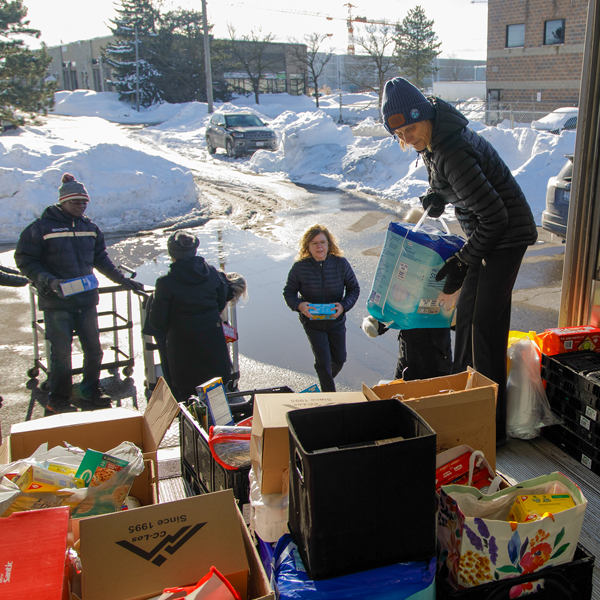 People load food boxes into a vehicle for community distribution.