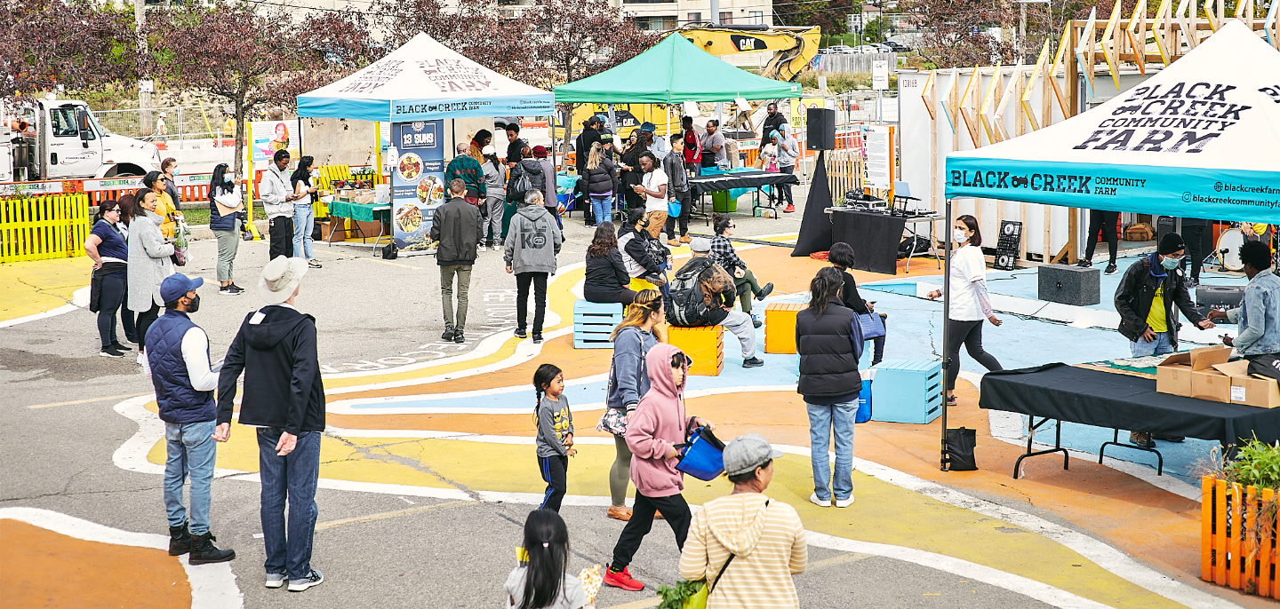 People milling about tents in Jane Finch Corner Commons site at the Jane Finch mall