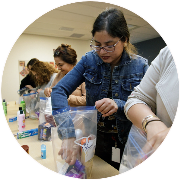 Group of women packing care kits with items like shampoo and deoderant