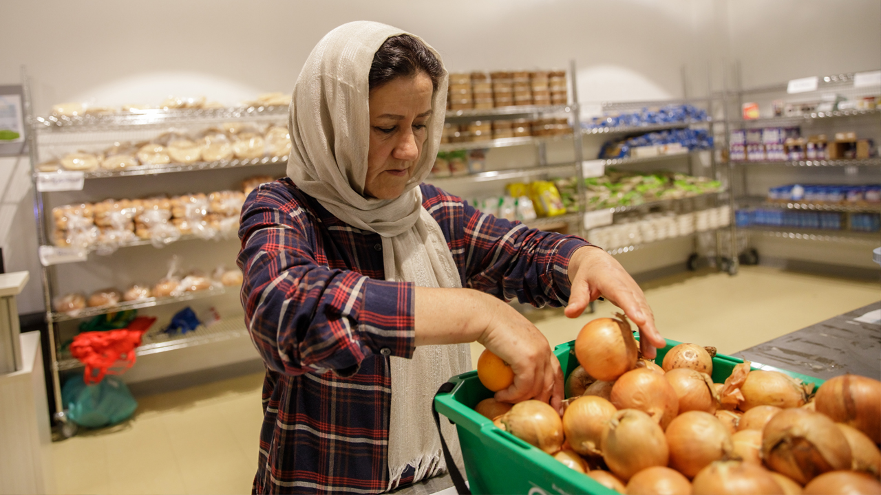 Woman-picks-an-onion-from-a-bin-at-Thorncliffe-Park-Community-Hub