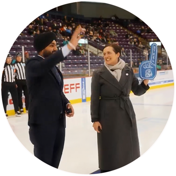Hardeep Grewal, MPP for Brampton East, and Heather McDonald, CEO of United Way Greater Toronto, stand on the ice at a Brampton Steelheads charity hockey game.