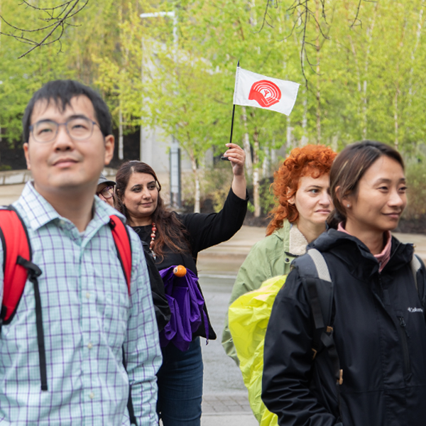 Participants on a United Way neighbourhood tour walk with a staff person holding a United Way flag.