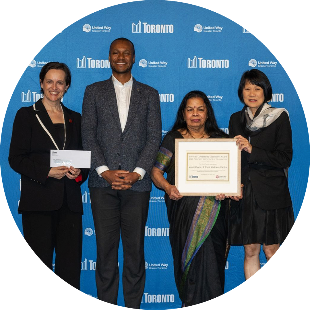 Circle shaped photo of two recipients of the 2025 Toronto Community Champion Awards, standing next to United Way President & CEO Heather McDonald and Toronto Mayor Olivia Chow, who is holding a plaque.