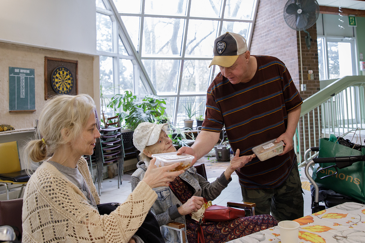 Ted hands out food to two women