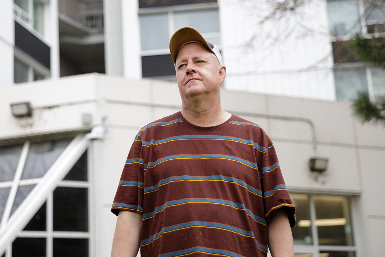 Ted stands in front of his apartment building