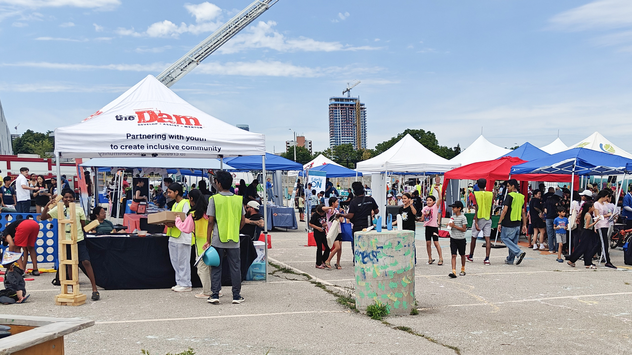 Various covered stall set up in a parking lot with crowds of people for the 2025 Cooksville Community Festival.