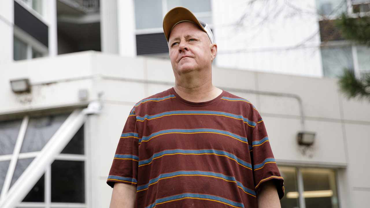 Ted stands in front of his apartment building.