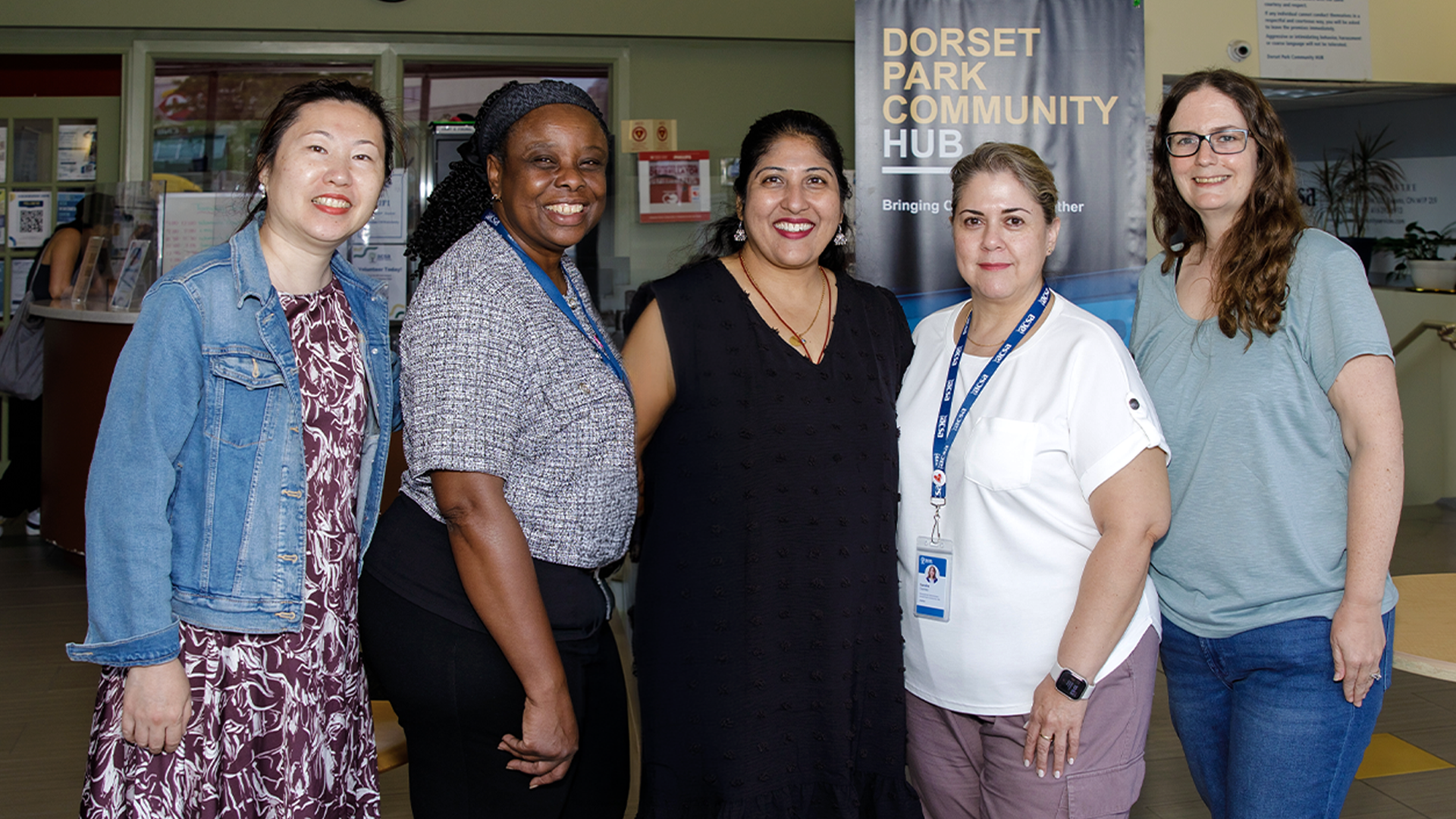 From left: Emily, Yvette, Suganthini, Sandra and Laura stand together smiling for a group photo at Dorset Park Community Hub.