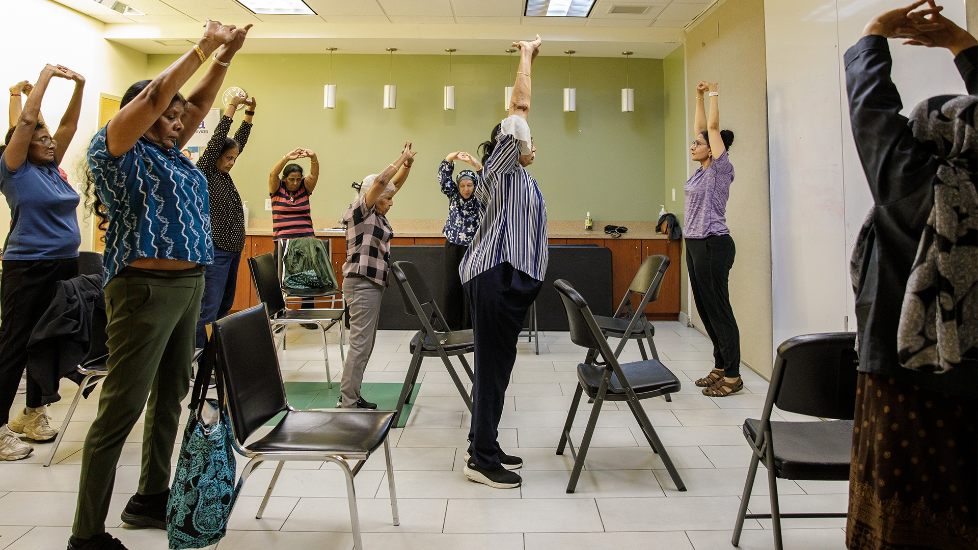 People stretch inside a room at Dorset Park Community Hub while participating in a yoga class.