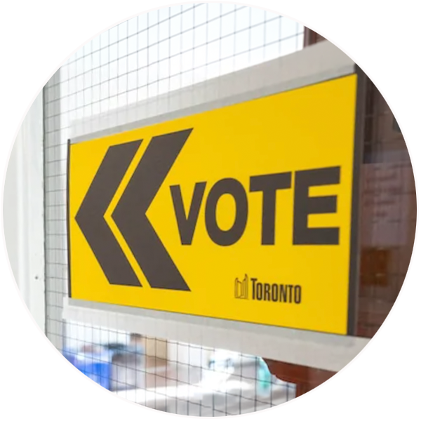 A yellow City of Toronto voting sign with two arrows pointing left and the word “VOTE” displayed in bold black lettering.