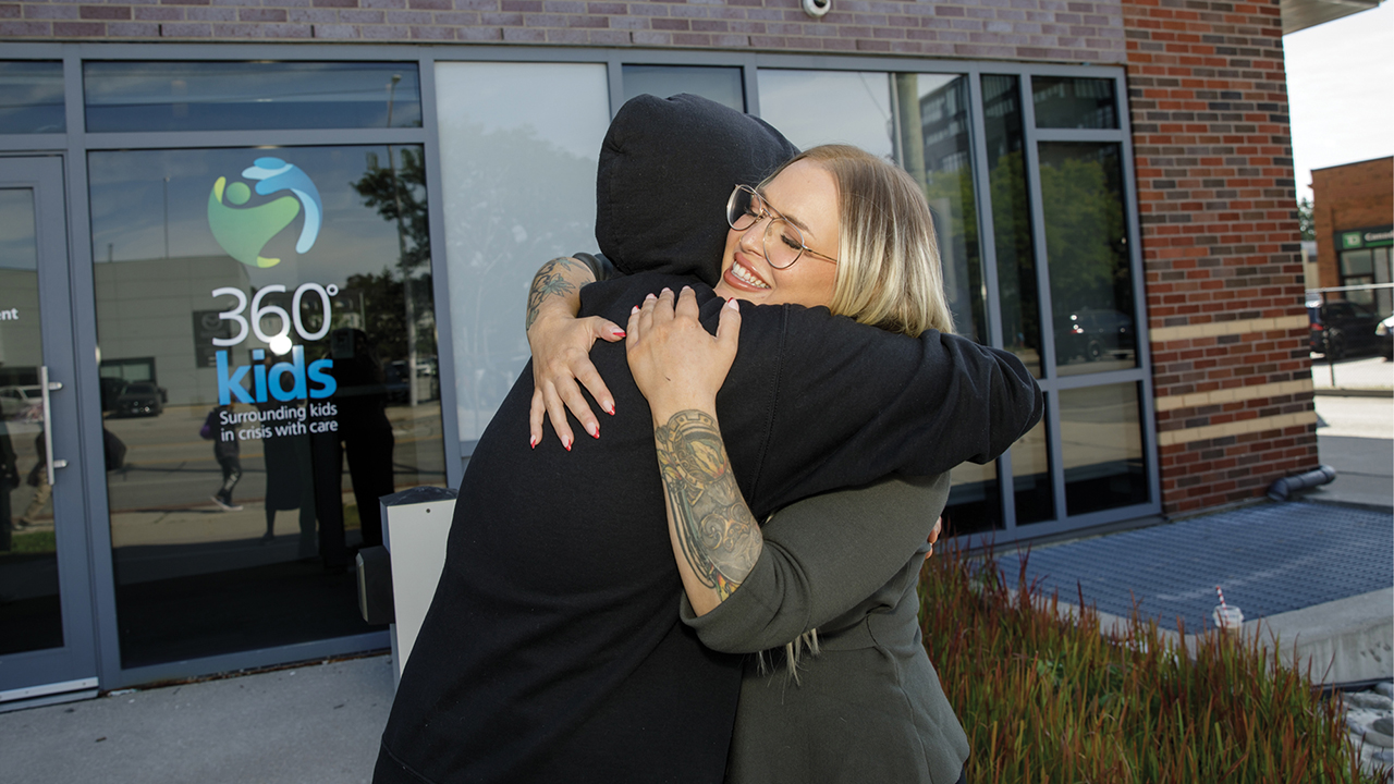 A 360°kids prevention worker named Erica hugging a client experiencing housing instability outside their building.