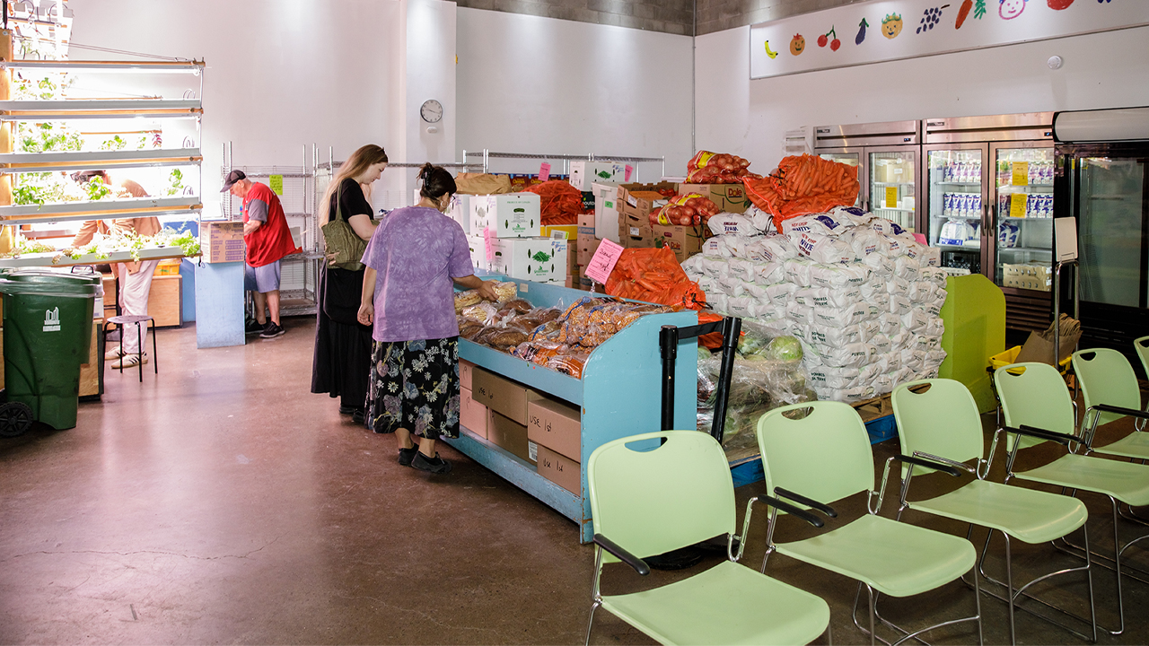 People examine bread among other bins of food near a waiting area