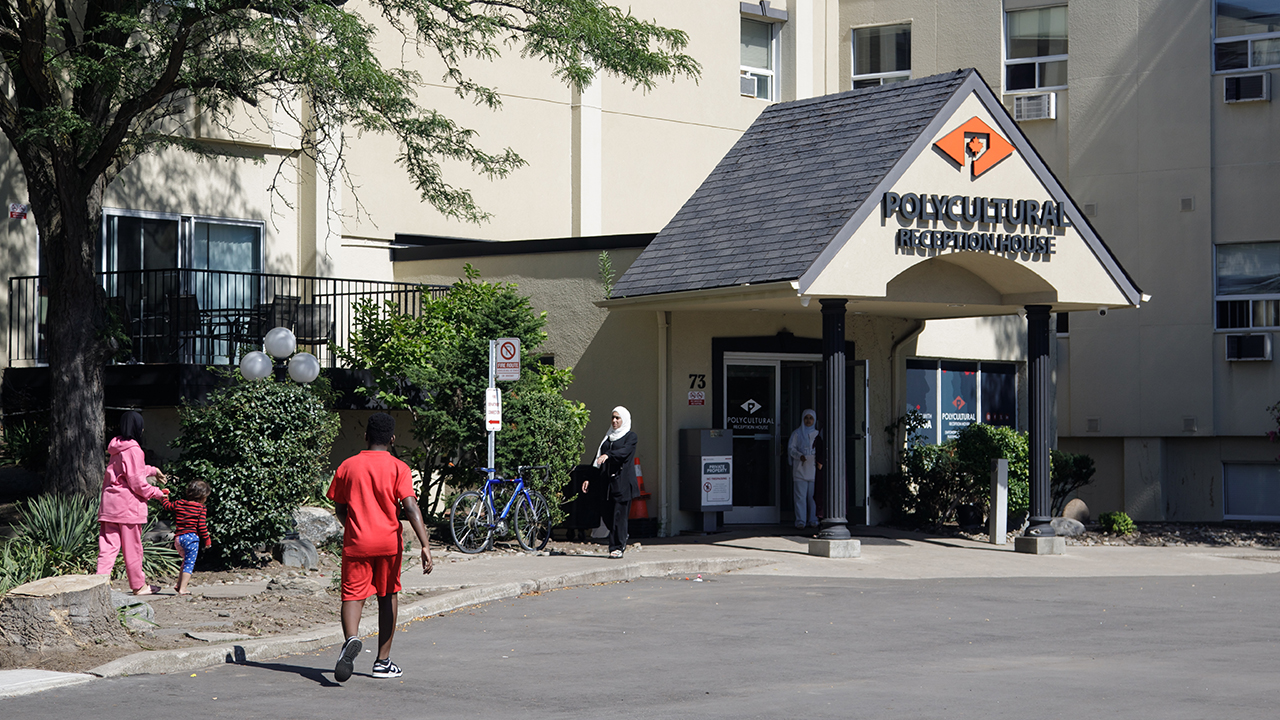 People of different nationalities enter and exit a building with a sign reading "Polycultural Reception House"