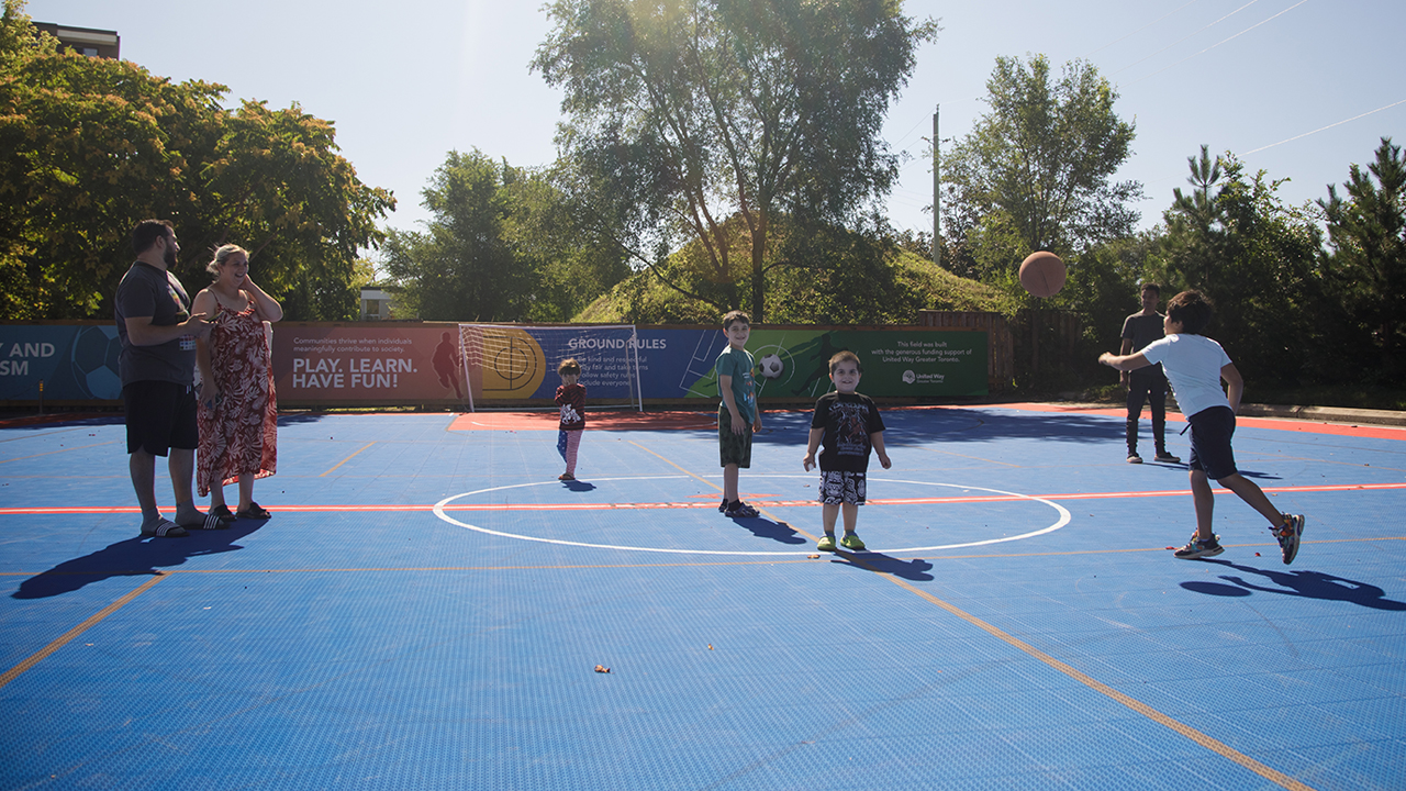Children of varying ages and their families gather on a basketball court
